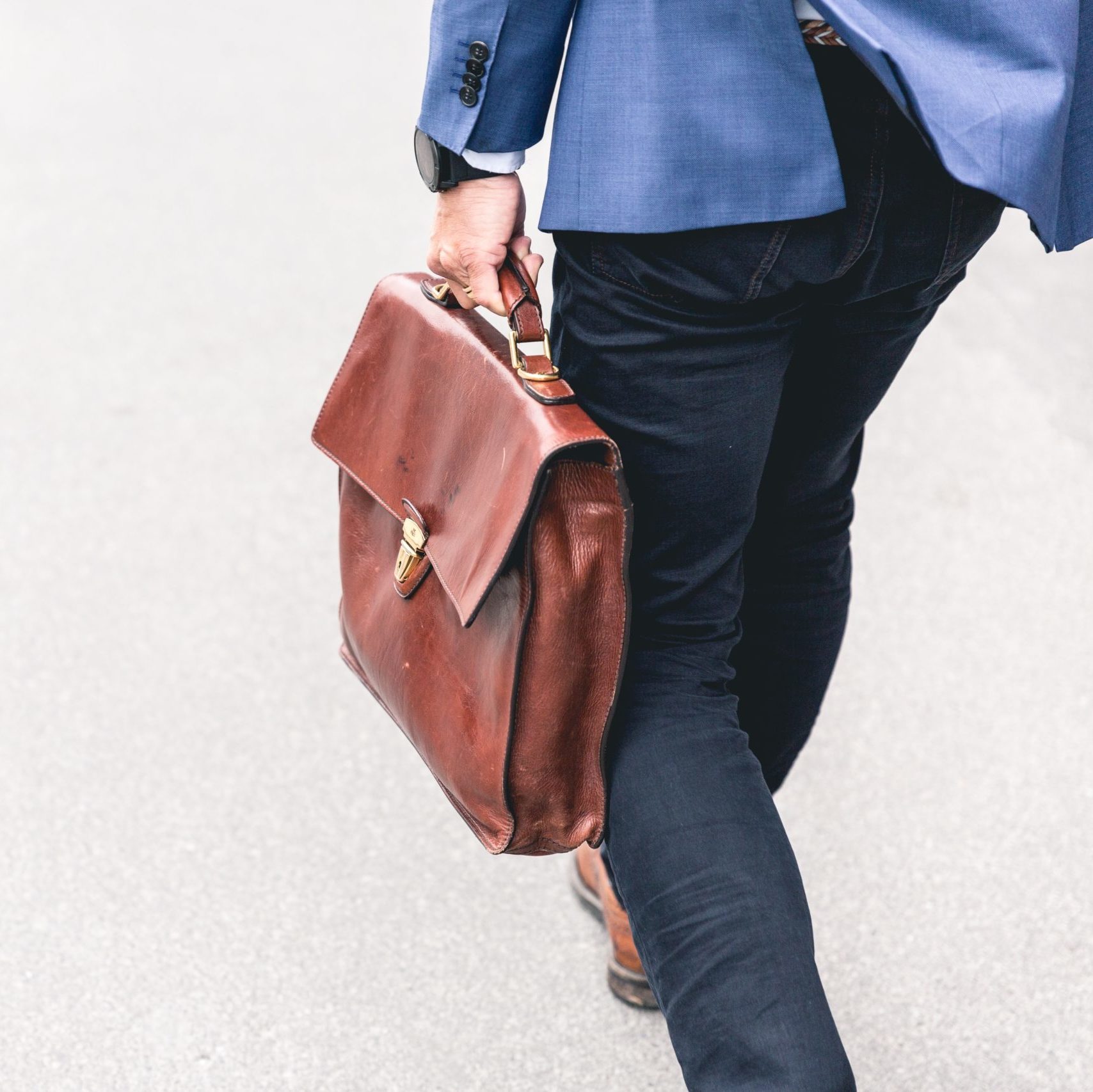 person walking holding brown leather bag