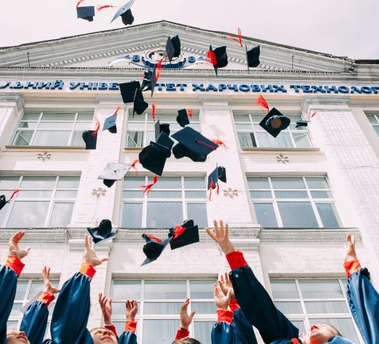 group of fresh graduates students throwing their academic hat in the air